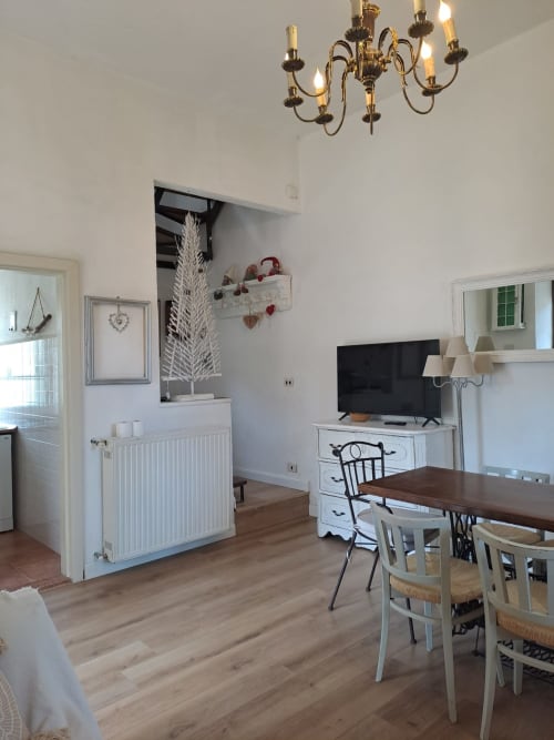Luminoso salotto dello Chalet Mini Momosa di Ovindoli con tavolo da pranzo, TV, camino e elegante lampadario