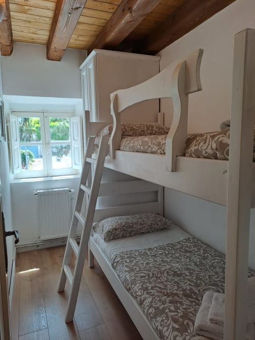 Camera da letto con letti a castello in legno, biancheria decorata e scala bianca presso l'Antico Chalet Momosa a Ovindoli