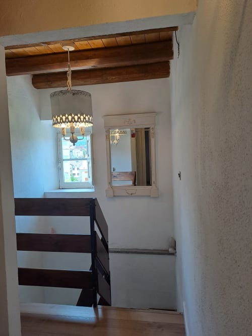Scala con travi in legno e lampadario in stile rustico nella villa Antico Chalet Momosa, rifugio di montagna a Ovindoli