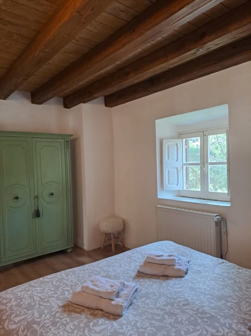 Accogliente camera da letto all'Antico Chalet Momosa di Ovindoli con travi in legno a vista, armadio verde e vista montagna