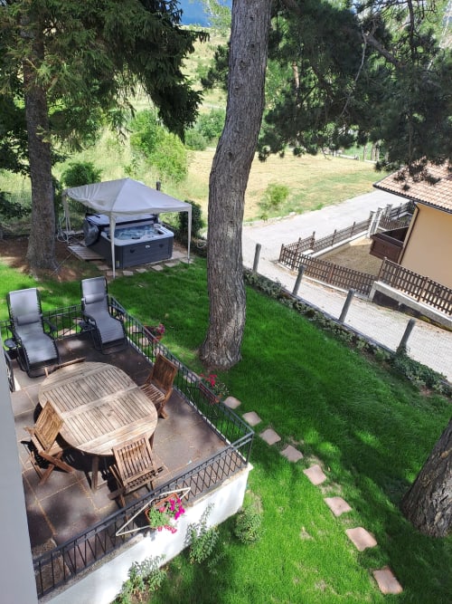 Villa Antico Chalet Momosa a Ovindoli con vasca idromassaggio, patio e vista sulle montagne circondata da sempreverdi