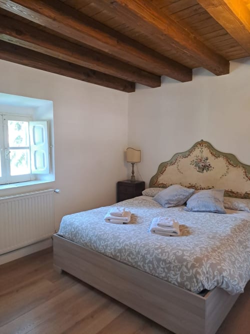 Camera accogliente all'Antico Chalet Momosa di Ovindoli con travi in legno a vista, testata decorativa e viste sulle montagne