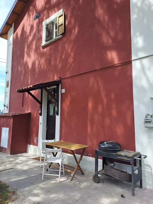 Antico Chalet Momosa a Ovindoli con facciata rossa, tavolo da pranzo, grill e vista sulla montagna