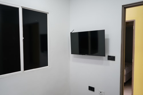 Habitación moderna del hotel Casa Mango en Cali con TV montada en pared y decoración minimalista