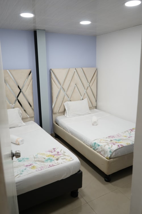 Dos camas gemelas con cabeceros color crema y ropa de cama floral en una habitación moderna del hotel Casa Mango, Cali