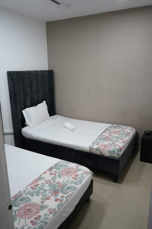 Dos camas gemelas con cabeceras negras y ropa de cama con estampado floral en el hotel Casa Mango de Cali