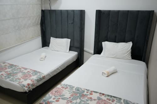 Dos camas dobles con cabeceras negras y ropa de cama blanca en el hotel Casa Mango de Cali, Colombia