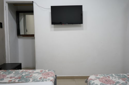 Habitación doble en el hotel Casa Mango de Cali con televisor de pared y entrada al baño