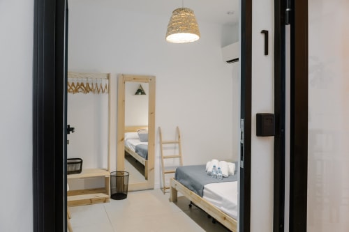 Habitación moderna en Stay Gest Valencia con cama de madera, espejo, lámpara colgante y decoración minimalista