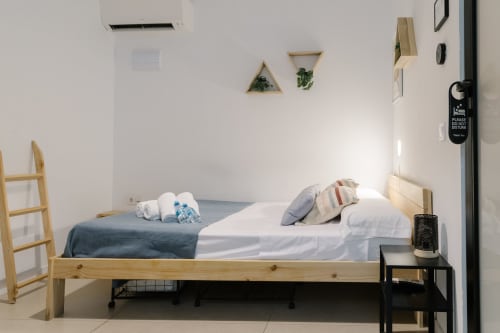 Dormitorio minimalista y luminoso en Stay Gest Valencia con cama de madera, sábanas blancas y comodidades modernas