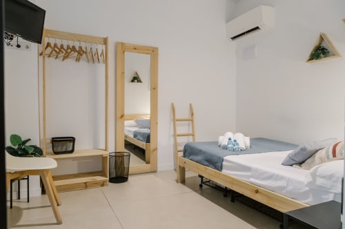 Dormitorio moderno en Stay Gest Valencia con camas de madera, espejo, aire acondicionado, TV y decoración minimalista