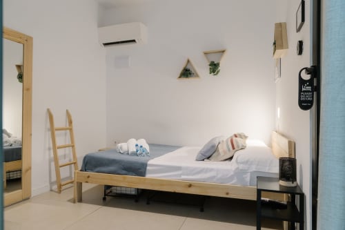 Luminosa habitación moderna de Stay Gest Valencia con cama de madera, paredes blancas, aire acondicionado y decoración minimalista