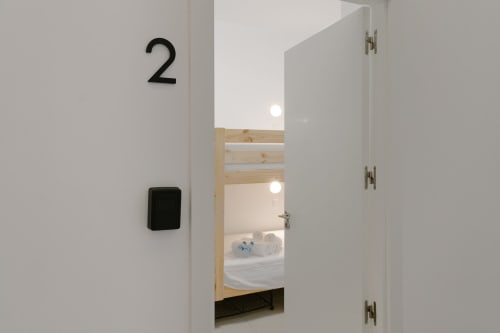 Entrada de la Habitación 2 en Stay Gest Valencia, puerta abierta mostrando cama con ropa de cama blanca