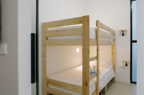 Literas de madera con ropa de cama blanca en una moderna habitación compartida de Stay Gest Valencia, España