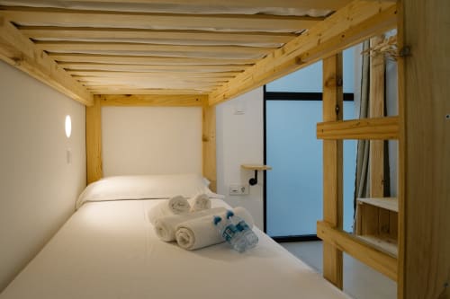 Cama pod de madera con ropa de cama blanca y toallas en el hotel Stay Gest de Valencia, España