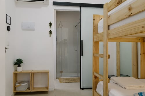 Habitación moderna en el hostal Stay Gest Valencia con cama litera de madera, baño privado y mobiliario minimalista