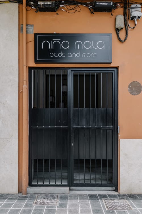 Fachada naranja con puertas enrejadas negras de la tienda Niña Mala en Valencia