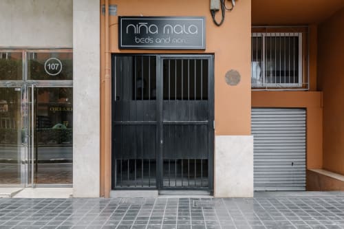 Fachada de la tienda Niña Mala en Valencia, España, con entrada de puertas negras y fachada naranja y blanca