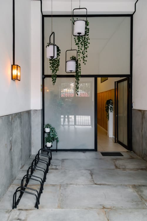 Entrada moderna de Stay Gest Valencia con puertas de vidrio y marco negro, macetas colgantes y zona de descanso minimalista
