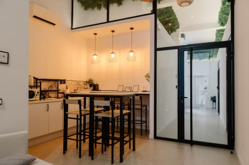 Moderna cocina y comedor en Stay Gest Valencia con barra negra, luces colgantes y puertas de cristal hacia sala contigua