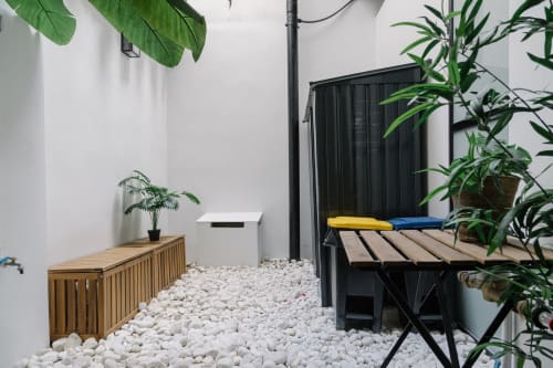 Patio minimalista moderno de Stay Gest Valencia con guijarros blancos, banco de madera, plantas en macetas y silla lounge negra