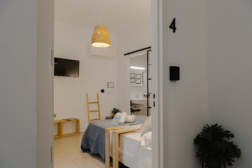 Dormitorio accesible en Stay Gest Valencia con cama, muebles de madera, lámpara colgante y baño privado visible