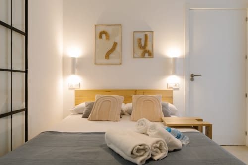 Habitación accesible en Stay Gest Valencia con cabecero de madera, toallas enrolladas, arte decorativo en la pared e iluminación moderna