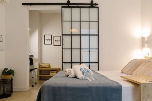 Habitación accesible en Stay Gest Valencia con cama, puerta ventana con rejilla, muebles de madera y comodidades modernas