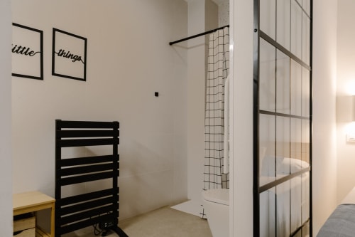 Habitación accesible en Stay Gest Valencia con toallero negro, escritorio amarillo y moderno plato de ducha