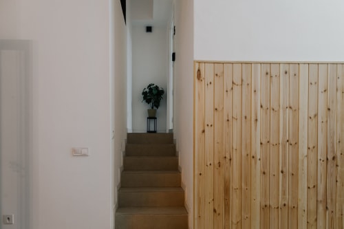 Escalera con barandilla de madera en el hotel Stay Gest de Valencia, planta con maceta en el descansillo, diseño minimalista moderno