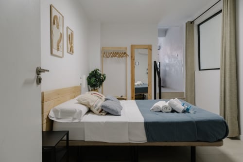 Dormitorio moderno en Stay Gest Valencia con cama de madera, ropa de cama fresca, espejos y decoración contemporánea