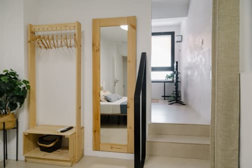 Recibidor moderno en Stay Gest Valencia con perchero de madera, espejo y acceso al dormitorio con cama visible
