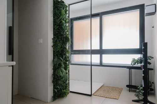 Entrada moderna del baño en Stay Gest Valencia con puertas de cristal, jardín vertical y accesorios contemporáneos