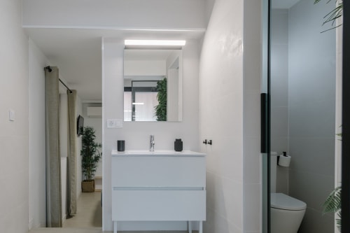 Baño moderno en Stay Gest Valencia con lavabo blanco, espejo iluminado y ducha de efecto lluvia en la habitación 5