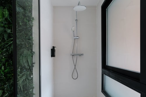 Cuarto de baño moderno en Stay Gest Valencia con ducha de lluvia, alcachofa manual y accesorios cromados en ambiente luminoso