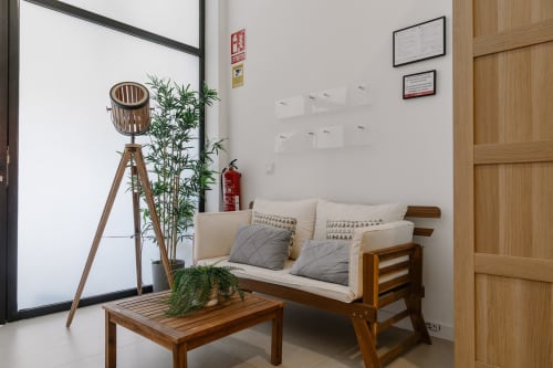 Acogedor salón en Stay Gest Valencia con sofá de madera, lámpara de pie, plantas en maceta y mesa de café