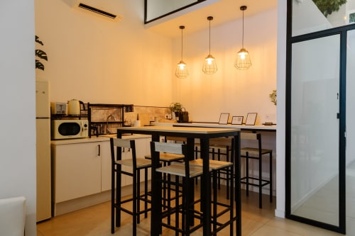 Moderna cocineta con barra negra, luces colgantes y electrodomésticos en habitación del hotel Stay Gest Valencia