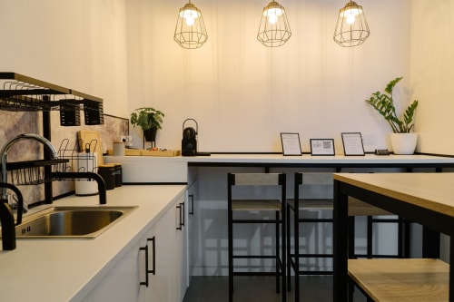 Moderna cocina en Stay Gest Valencia con luces colgantes, encimeras de madera, plantas y asientos tipo barra