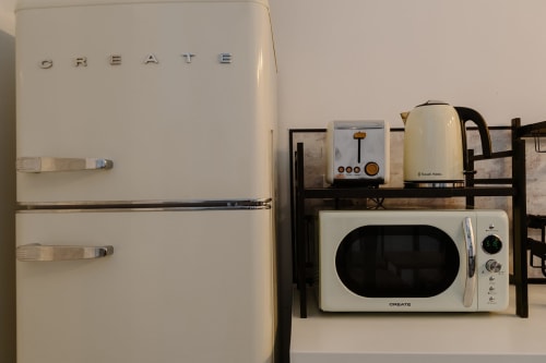Refrigerador y microondas Smeg color crema de estilo retro en habitación con kitchenette del hotel Stay Gest Valencia