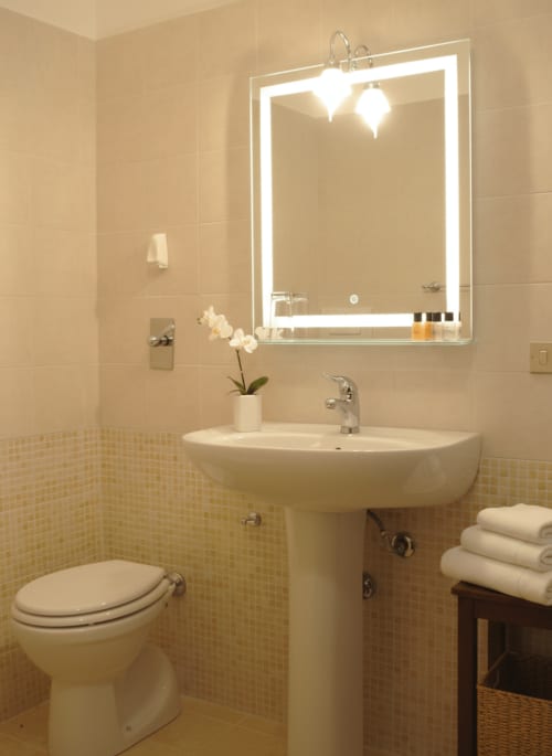 Bagno elegante della Camera Doppia Classic di Candalù Hotel, Valderice, con specchio illuminato, lavabo su colonna e piastrelle color crema