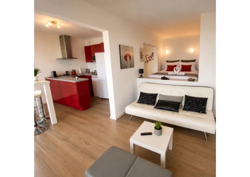 Loft moderne à Agde avec cuisine rouge, canapé blanc et chambre vue mer