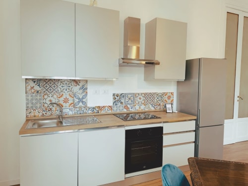 Cucina moderna dell'Hotel Candalù a Valderice con mobili bianchi, piano in legno e piastrelle decorative a motivi