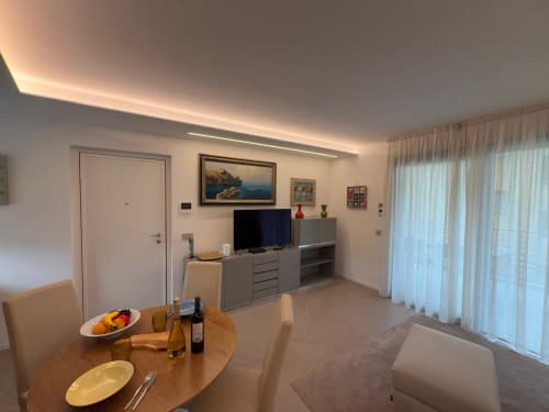 Moderno salotto con zona pranzo, TV, angolo cottura e vista giardino presso Holiday Home Garda Trentino ad Arco