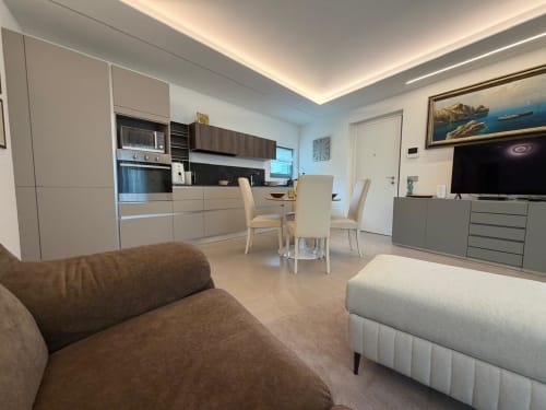 Moderno appartamento open-plan a Holiday Home Garda Trentino ad Arco con cucina, zona pranzo e soggiorno con divano e TV