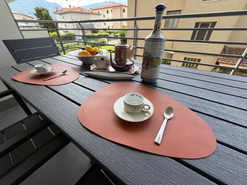 Terrazza in stile cena presso La Carezza di Arco con tavoli apparecchiati, tazza di tè e vedute montane ad Arco, Italia