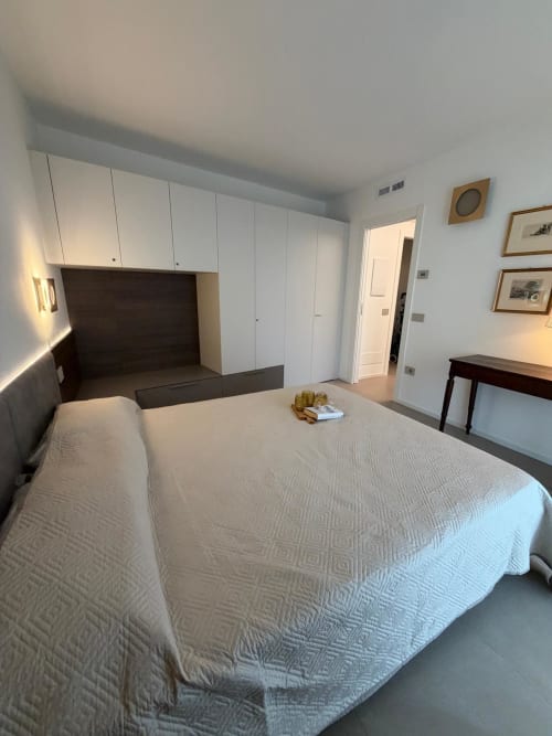 Camera moderna a La Carezza di Arco con letto queen-size, armadio integrato, testata scura e vista sul giardino in Trentino.