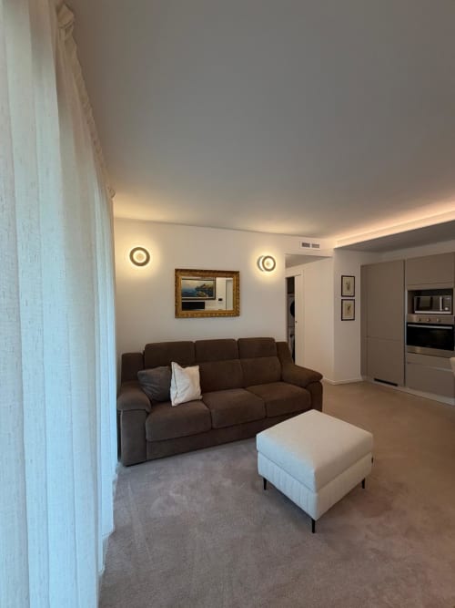 Soggiorno moderno con divano marrone e pouf bianco presso Holiday Home Garda Trentino, Arco