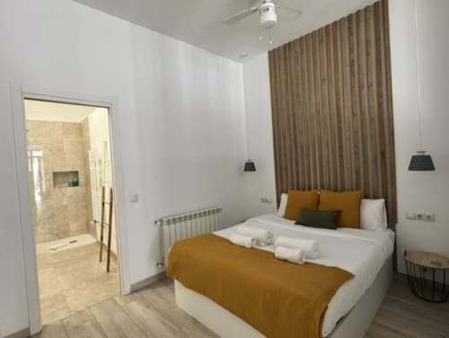 Dormitorio moderno en Artbel Rentals Madrid con cama queen, detalles dorados, baño ensuite y mobiliario contemporáneo