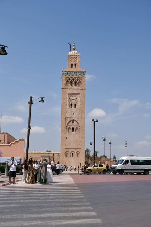 Koutoubia Mosque minaret in Marrakech with tourists and vehicles in plaza near Riad 191