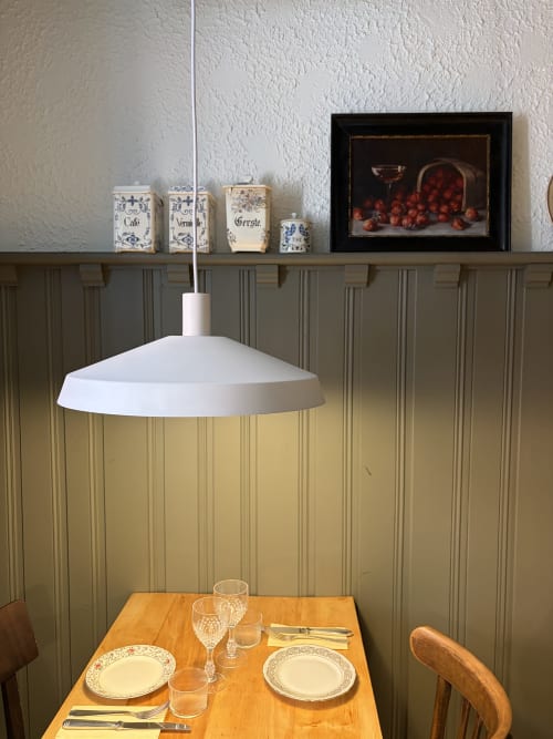 Élégante mise en table à l'Hôtel l'Ange : suspension blanche au-dessus d'une table dressée en porcelaine fine